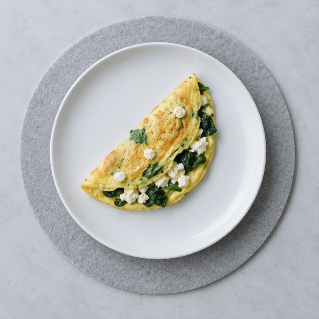 Steak with broccoli and a small plate of boiled eggs served plainly on white plates on a grey mat