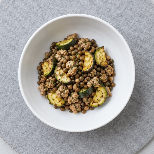 A protein-first meal prep bowl plated on a white plate with chicken, quinoa and roasted vegetables