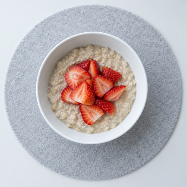 Low FODMAP breakfast of strawberry oatmeal on a white plate with calories and protein shown, honest home plating